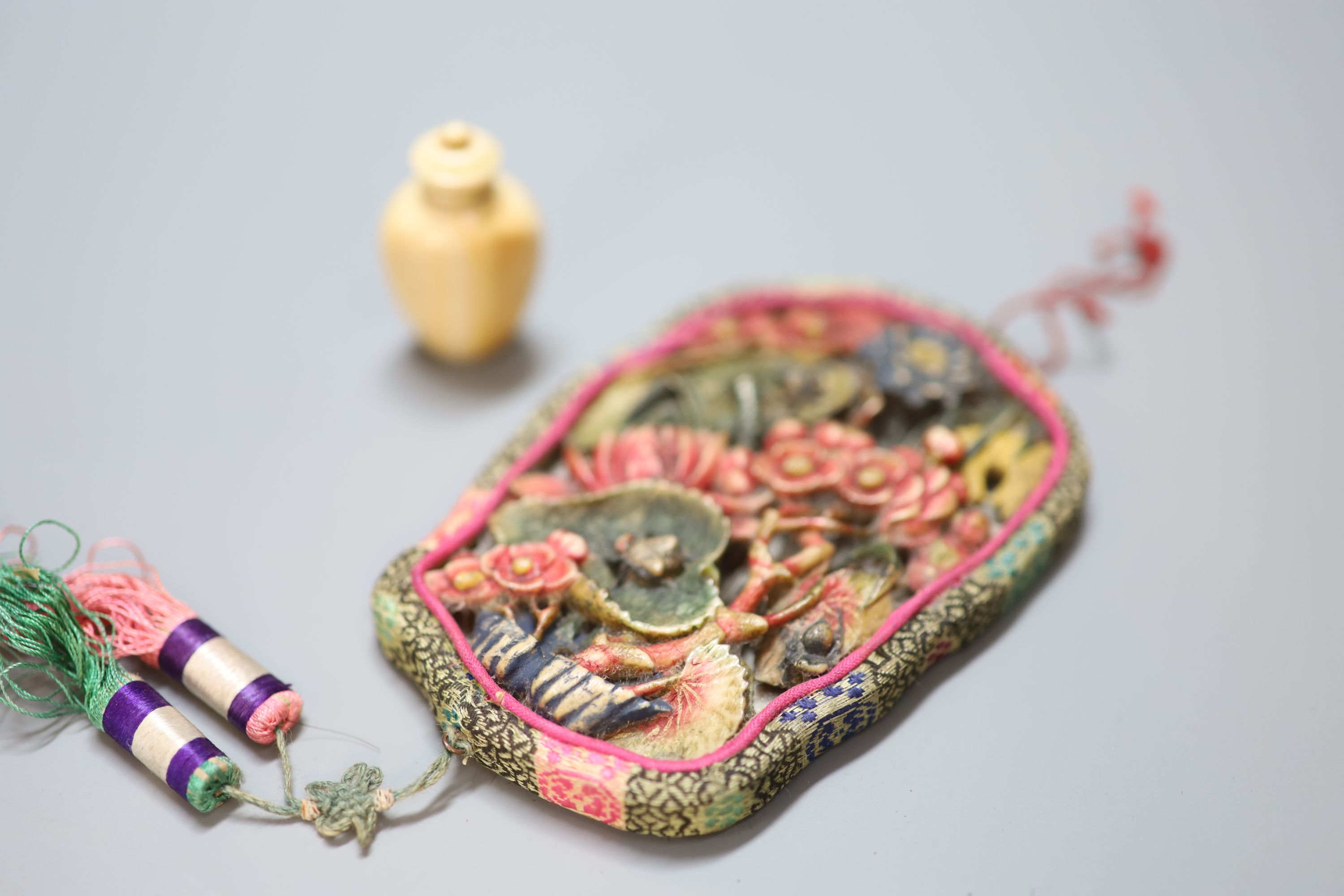 An early 20th century Chinese carved ivory or horn plaque mounted as a mirror and a snuff bottle